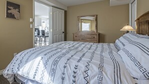 Un dormitorio con una cama, un aparador, un espejo y una lámpara.
