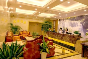 A hotel lobby with a reception desk, seating area, and a large wall mural. - Siyuan Hotel (Chishui)