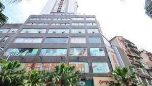 A multi-story building with commercial signage on the ground floor, surrounded by palm trees. - Siyuan Hotel (Chishui)