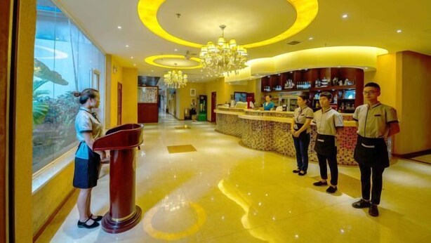 A hotel lobby with a reception desk, staff members, and a large chandelier. - Siyuan Hotel (Chishui)
