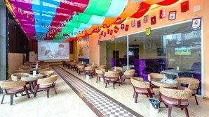 A restaurant with wicker chairs and tables, a checkered floor, and colorful ceiling decorations. - Siyuan Hotel (Chishui)