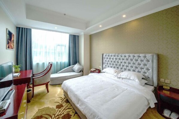 Una habitación de hotel con una cama, un escritorio, una silla y un televisor.