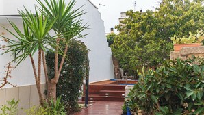 A wooden deck leading to a pool, surrounded by various plants and a white wall. - Exclusive Private Villa with Pool & Jacuzzi Surrounded by Citrus Trees – Salento (Taviano)