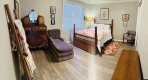 A bedroom with a wooden bed, a dresser, a chair, and a bench.
