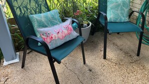 Deux chaises d’extérieur avec des coussins de couleur turquoise et un motif floral, une plante en pot et une terrasse en béton.