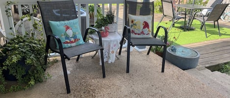 A patio with two chairs, a small table, and a decorative fence.