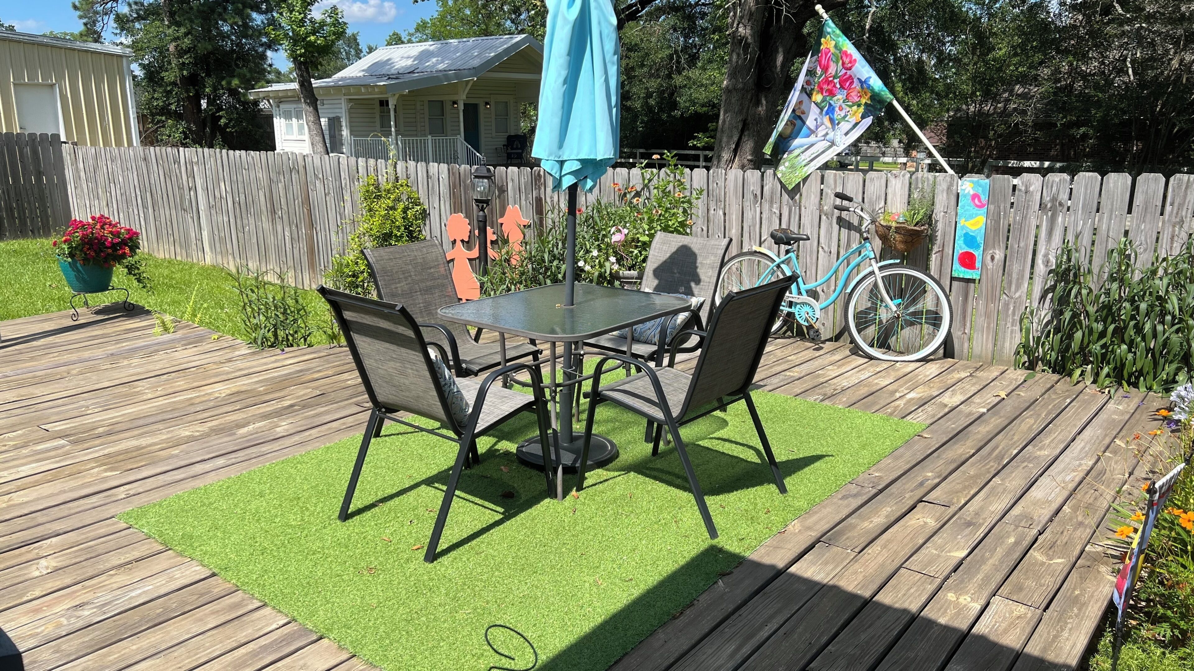 A patio with a table and chairs, a bicycle, and a wooden fence.