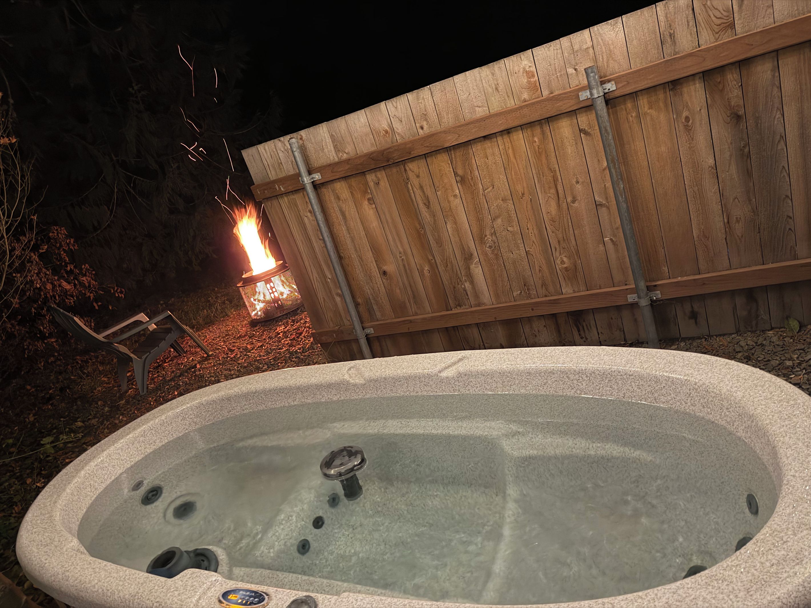 A hot tub with a wooden fence in the background.