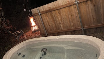 A hot tub with a wooden fence in the background.