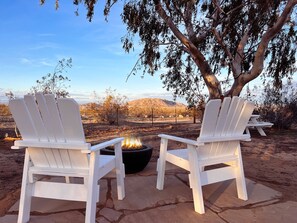 Two white Adirondack chairs facing a fire pit with a view of a desert landscape and mountains in the background. - Kick back at The Easy Does It Ranch - fast internet (Landers)