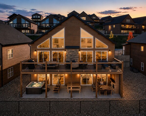 Ein zweistöckiges Holzhaus mit Balkon, Whirlpool und einer Steinmauer.