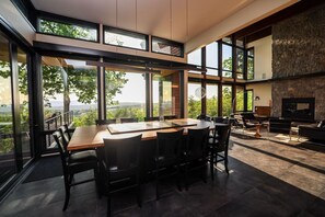 Een modern interieur met een grote eettafel, zwarte stoelen en een stenen openhaard.