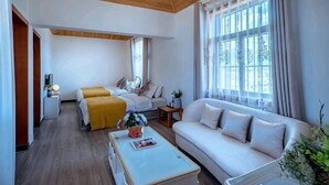 A modern hotel room with a wooden ceiling, a sofa, a bed with a yellow blanket, a white coffee table, and large windows. - Jiayu Seascape Inn (Dali City)
