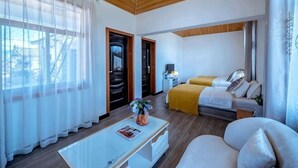 A hotel room with a bed, a sofa, a coffee table, and a window with curtains. - Jiayu Seascape Inn (Dali City)