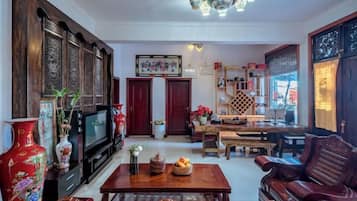 A traditional living room with a television, wooden furniture, and a chandelier.