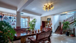 A spacious living area with a wooden bench, a coffee table, and a chandelier. There is a staircase with a railing and a potted plant. - Jiayu Seascape Inn (Dali City)