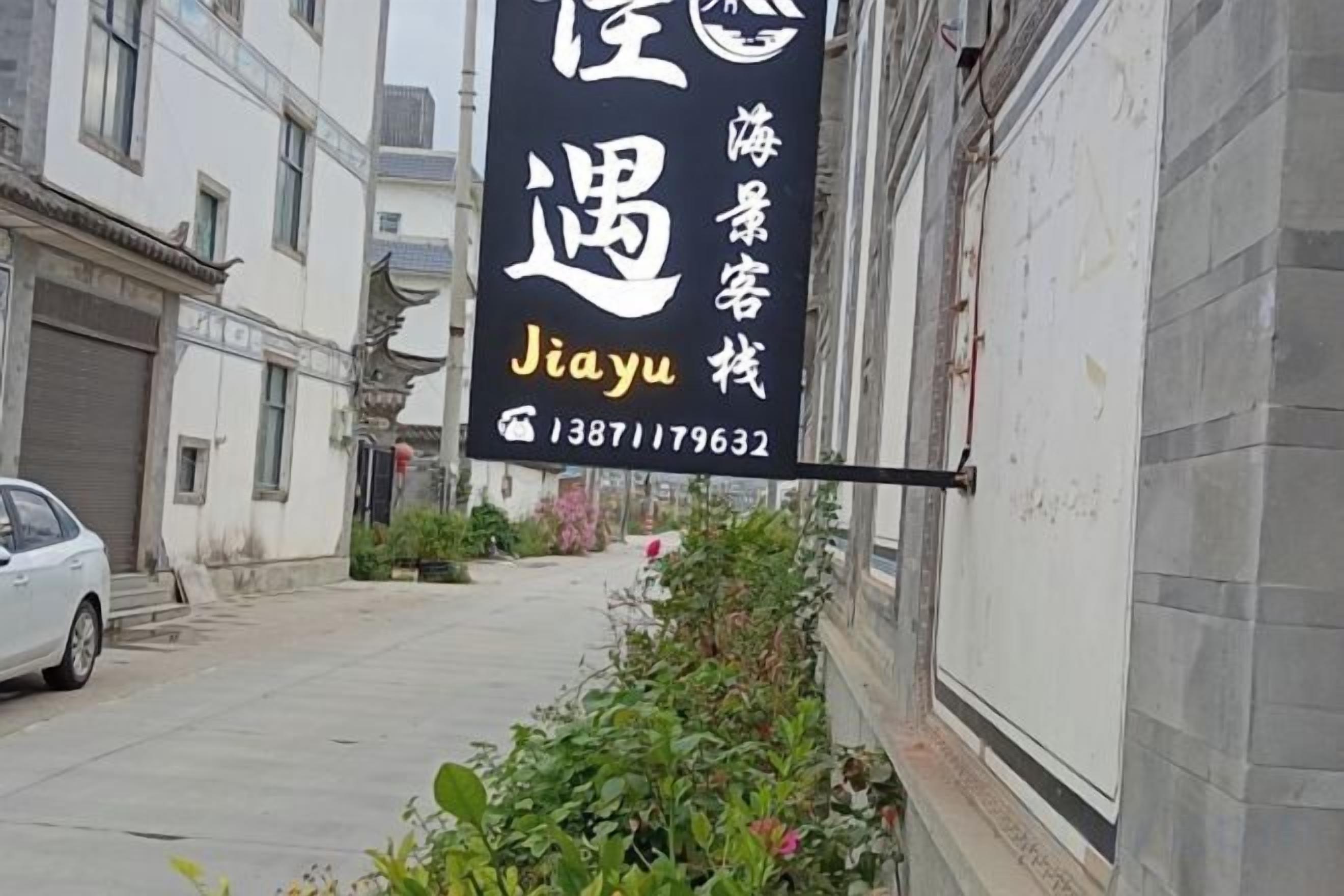 A black sign with white and yellow text advertising a hotel named 'Jiayu' with a contact number.