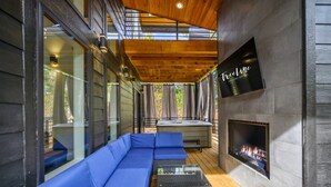 Un espacio moderno al aire libre con un sofá azul, un jacuzzi y una chimenea.