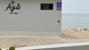 A building named 'Azul Café - Bistro' with a sign for 'Tramonto Hotel Abierto' and a view of the beach. - Classy Queen w/ramp access. Balcony subject to the sound of waves (La Ceiba)