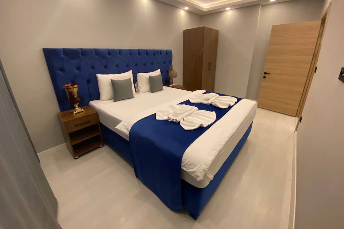 A modern bedroom with a blue headboard, a wooden wardrobe, and a wooden door.
