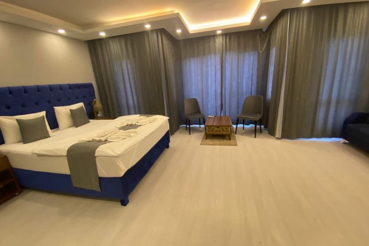 A bedroom with a large bed, two chairs, a small table, and a sofa.