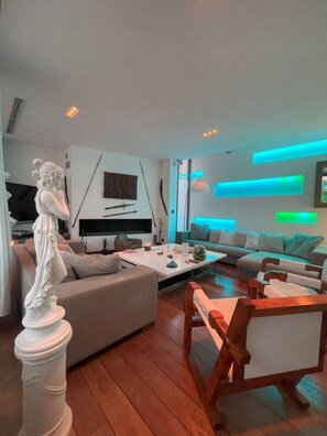 A modern living room with a statue, a sofa, a coffee table, and a TV.