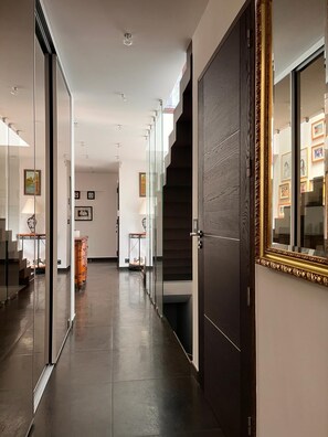 A modern hallway with glass doors, a dark wooden door, and a staircase.