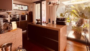 Uma cozinha moderna com ilha central, eletrodomésticos embutidos e uma grande janela com vista para um jardim.