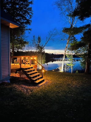 A wooden deck with outdoor seating and a staircase leading to a house.
