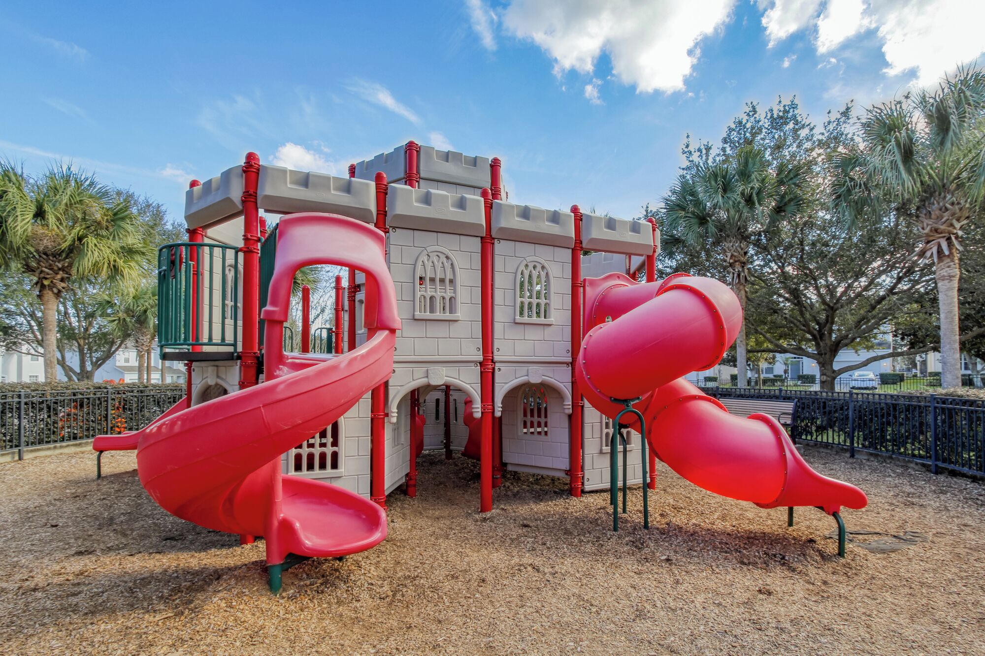 A playground with a castle-themed play structure, including slides and climbing elements.