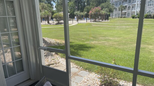Un invernadero con vistas a un césped cuidado y un edificio de piedra al fondo.
