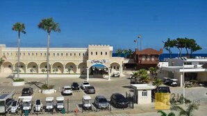 Un hotel con un cortile centrale, palme e vista diretta sul mare.
