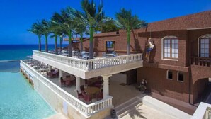 Un hotel sulla spiaggia con un balcone, palme e vista sull'oceano.