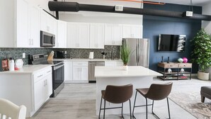A modern kitchen with white cabinets, stainless steel appliances, and a central island with bar stools.