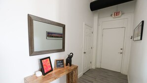 A hallway with a wooden console table, a mirror with a decorative frame, and an exit sign.