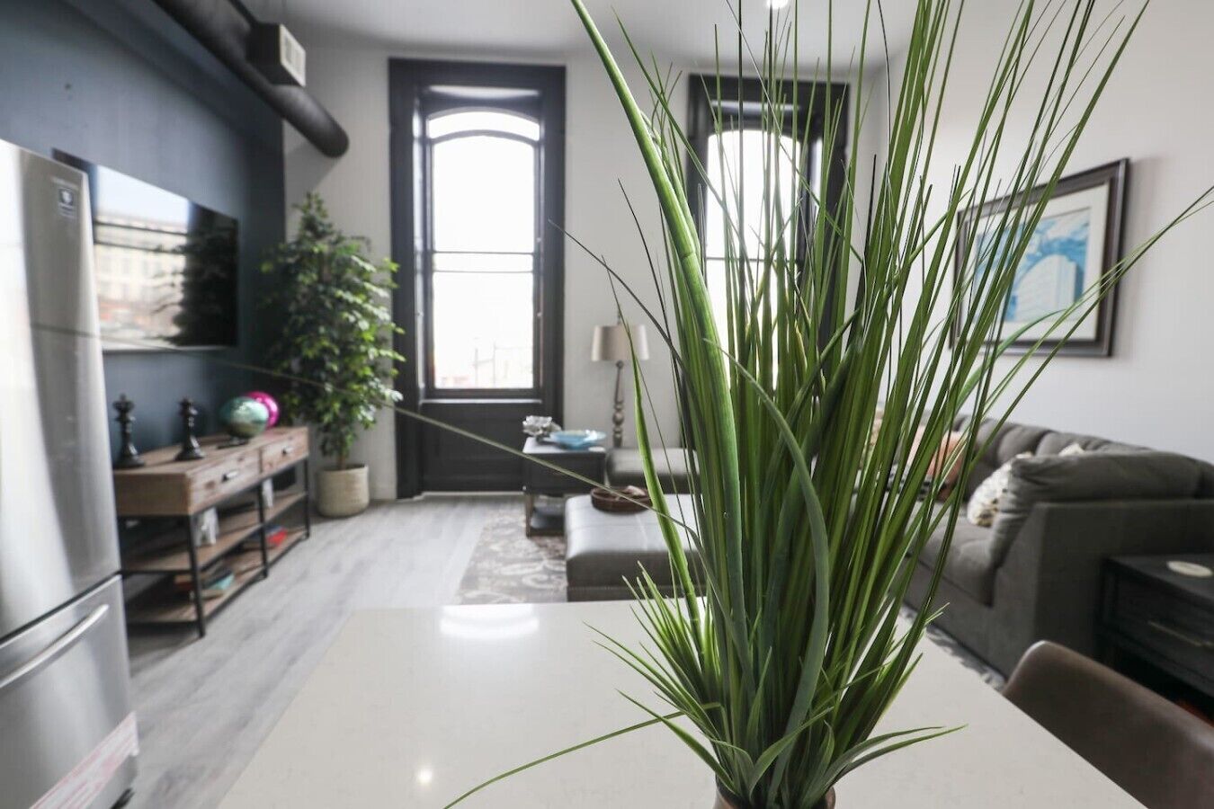 A modern living room with a large plant, a dining table, and a sofa.. 2B Stay at the Heart of Easton!