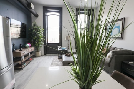 A modern living room with a large plant, a dining table, and a sofa.. 2B Stay at the Heart of Easton!