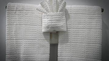 A white towel with a textured pattern, hanging on a wall.