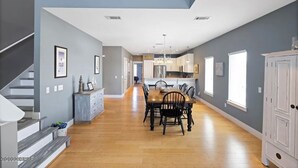A spacious kitchen with a dining area, wooden floors, and a staircase on the left.