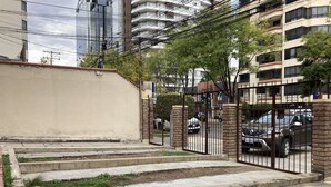 Zona residencial cerrada con escalones de hormigón que conducen a un camino de acceso, rodeada de edificios de varios pisos y líneas eléctricas.