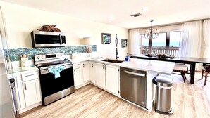 A modern kitchen with a microwave, oven, and dishwasher. There is a dining area with a view of the ocean. - Panoramic view of the sugar white sand and the sparkling Emerald waters (Port St. Joe)