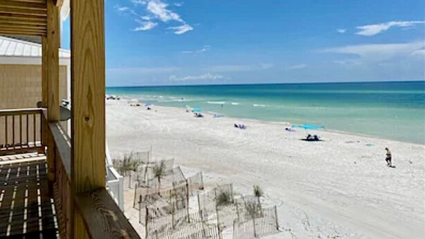A beach view from a wooden balcony with a clear sky. - Panoramic view of the sugar white sand and the sparkling Emerald waters (Port St. Joe)
