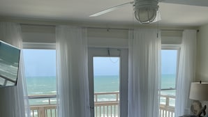 A bedroom with a large bed, a ceiling fan, and a view of the ocean through a sliding door. - Panoramic view of the sugar white sand and the sparkling Emerald waters (Port St. Joe)