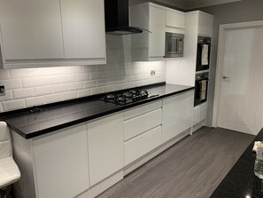 A modern kitchen with white cabinets, a black countertop, a gas stove, a microwave, and an oven.