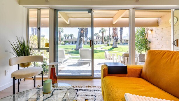 A modern living room with a sofa, a chair, and a glass table.