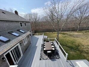 A deck with a table and chairs, a covered patio area, and a view of the backyard.