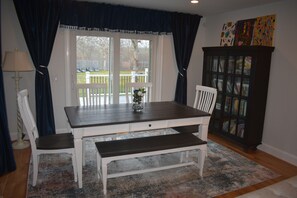 A dining area with a table, chairs, a bench, a rug, and a cabinet with books.