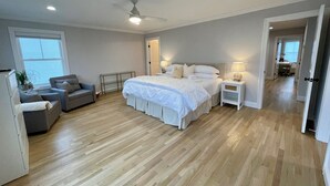 A spacious bedroom with a large bed, a ceiling fan, and a desk area with a chair. - Brand new house with water views just steps from beach! (Milford)
