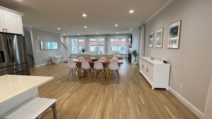 A spacious kitchen with a dining area, wooden flooring, and a view of the outside. - Brand new house with water views just steps from beach! (Milford)