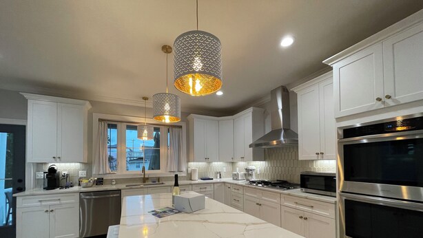 A modern kitchen with white cabinetry, a marble island, stainless steel appliances, and pendant lighting. - Brand new house with water views just steps from beach! (Milford)